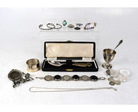 A group of silver and white metal comprising egg cup and spoon, cased spoon with initials engraved to the terminal, napkin ri