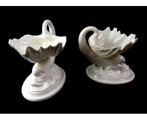 ROYAL WORCESTER; a pair of blanc de Chine salts in the form of dolphins balancing shells on their backs, each on oval bases, 