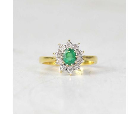 An 18ct yellow gold emerald and diamond cluster ring, the emerald weighing approx. 0.33ct, size K, approx. 2.6g.