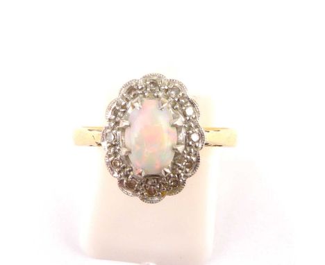 An 18ct gold opal and diamond ring, the claw set white opal with traces of green and red, in a white mount featuring tiny dia