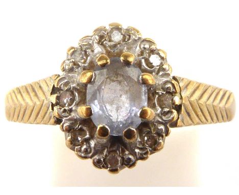 A 9ct gold dress ring with central blue stone in a border of tiny white stones, with arrow pattern shoulders, size M, approx.