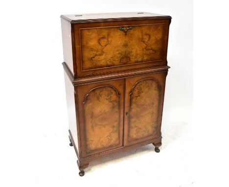 A mid-20th century Epstein-style walnut cocktail cabinet with pull-down front and automatic lift-up top, mirrored interior wi