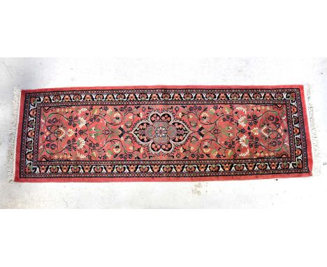 A contemporary woollen runner of small proportions, with all-over floral decoration within a stepped border, 200 x 63cm.Condi