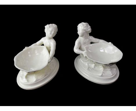 ROYAL WORCESTER; a pair of blanc de Chine salts in the form of a merboy and mermaid, each holding up a shell, on an oval base