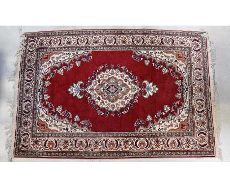 A red ground carpet with central medallion within floral border, 230 x 150cm.