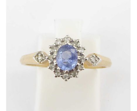 A 9ct gold dress ring with central blue claw set stone in a border of tiny diamonds and a small tiny diamond to each shoulder