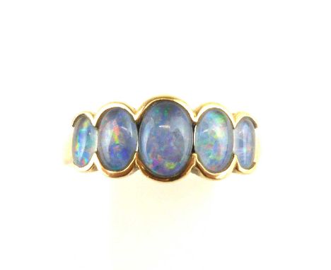 A 9ct gold crystal opal ring, the five graduated bezel set oval crystal opals with transparent back, showing blues, greens an