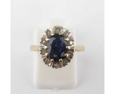 A 9ct gold diamond and sapphire ring, the claw set cut oval sapphire within a border of tiny illusion set diamond chips, size