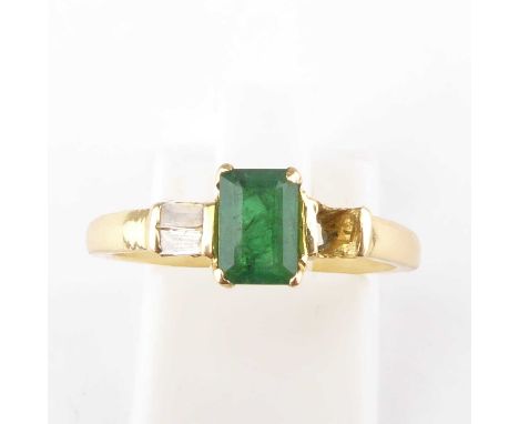 A gold diamond and emerald ring, the emerald cut claw set stone flanked by two tapered baguette cut diamonds (af), on a gold 