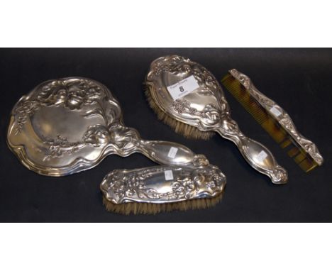 An Art Nouveau four-piece silver-mounted dressing set comprising a hand mirror, two brushes and a comb. All repoussé decorate