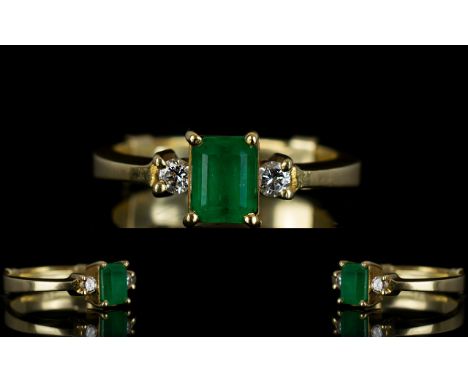 Ladies 18ct Gold Emerald and Diamond Dress Ring the central emerald of natural colour flanked by two round brilliant cut diam