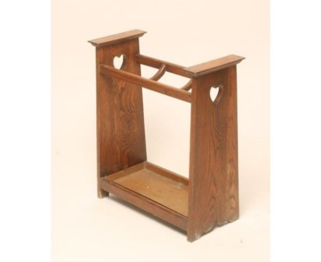 AN ARTS AND CRAFTS OAK STICK STAND of oblong form with dished dividers and lift out tray, the solid tapering sides extending 