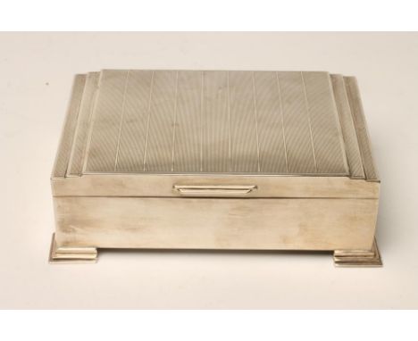 AN ART DECO SILVER CIGARETTE BOX, makers Bennett Ltd., Birmingham 1945, of oblong form, the hinged stepped cover with engine 