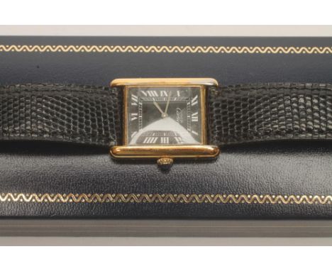 A MUST DE CARTIER SILVER GILT "TANK" WATCH, the oblong black dial with silvered Roman numerals in a plain case, the winding c