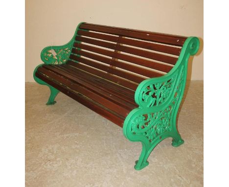 A VICTORIAN CAST IRON GARDEN BENCH with mahogany slatted seat and back, scroll back top rail, the pierced ends moulded with a