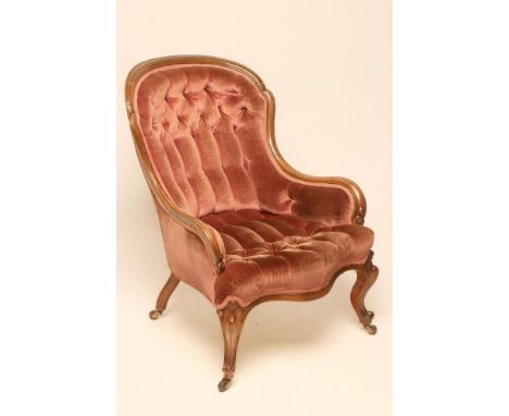 A LADY'S VICTORIAN WALNUT FRAMED ARMCHAIR of low spoonback form button upholstered in pink velvet, the channelled frame with 