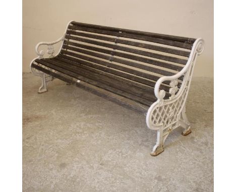 A VICTORIAN CAST IRON GARDEN BENCH with slatted wood seat and back, scroll back top rail, down curved arms on flower moulded 