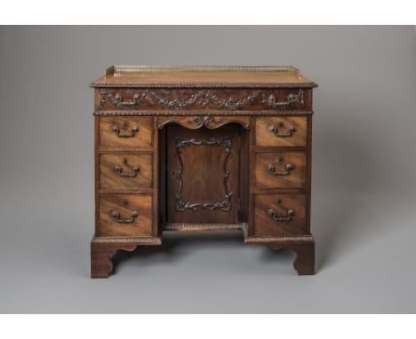 A GEORGIAN CARVED MAHOGANY KNEEHOLE DESK, late 18th century, the top with foliate carved edge and brass gallery, long fitted 
