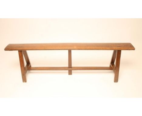 A RUSTIC FRUITWOOD BENCH, 19th century, the narrow single plank seat raised on splayed square section end supports joined by 