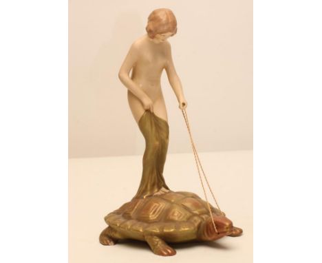 AN ART NOUVEAU ROYAL DUX BISQUE PORCELAIN FIGURE modelled as a naked maiden standing on the back of a tortoise, pink patch ma