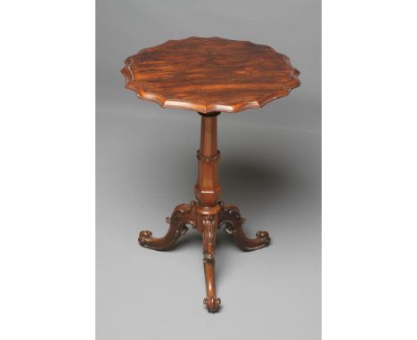 A VICTORIAN ROSEWOOD LAMP TABLE of circular form with moulded wavy edged top, turned tapering and faceted lotus carved stem, 