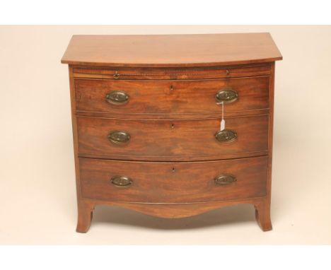 A GEORGIAN MAHOGANY BOWED CHEST, c.1800, the beaded edged brushing slide over three drawers, oval brass drop handles, shaped 