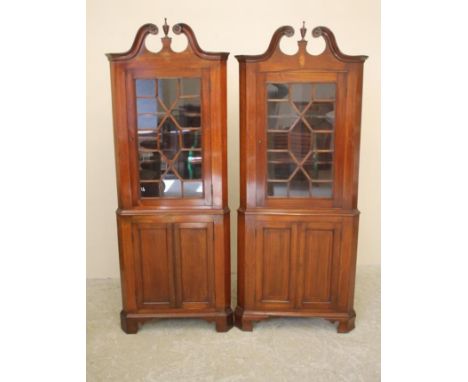 A MATCHED PAIR OF MAHOGANY AND STRING INLAID STANDING CORNER CUPBOARDS, early 20th century, the scrolled pediment with carved