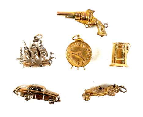 A group of 9ct yellow gold charms, comprising sailing ship, 24mm, revolver, 31mm, tankard, 14mm, alarm clock, and two motor c