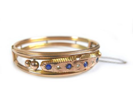 A Victorian yellow and rose gold hinged bangle, with an oval panel set with four 3.0mm blue sapphires, and diamond chips, a/f