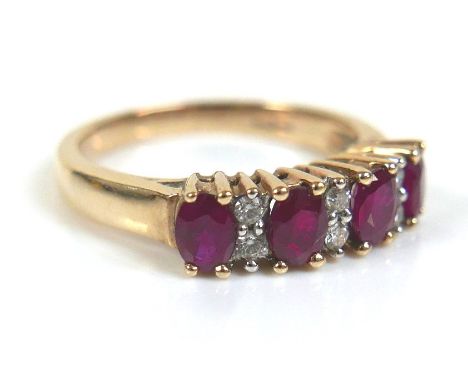 A 9ct yellow gold, ruby and diamond ring, a row of four oval cut rubies, each 4.5 by 3.5mm, separated by pairs of small diamo