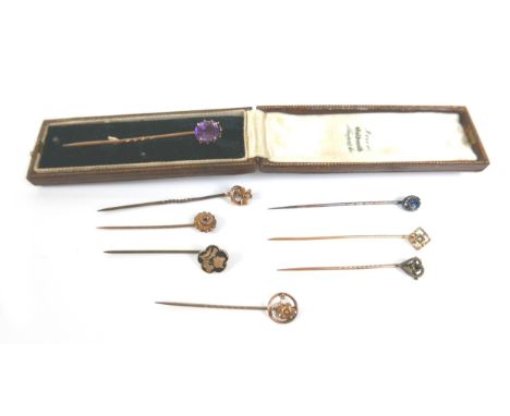 A group of gold and yellow metal stick pins, including one set with an amethyst, 6cm long, 8.6g combined weight, together wit