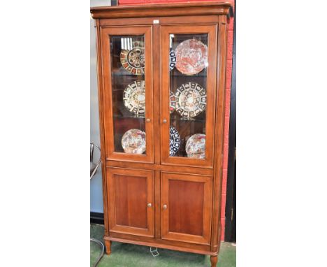 A contemporary Victorian style mahogany bookcase, rounded outswept cornice above a pair of glazed doors enclosing two adjusta