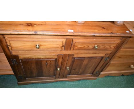 A 20th century pine sideboard, moulded rectangular top above two short drawers and a pair of raised and fielded panel doors e