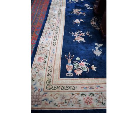 A Chinese style carpet, on a midnight blue ground, centred by a flowering vase surrounded by further flowers and foliage bord