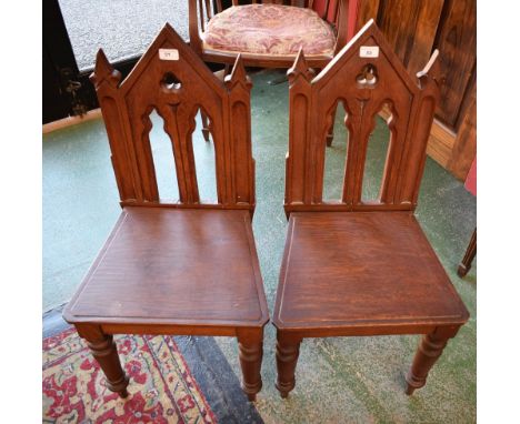 A pair of Gothic Revival oak hall chairs, architectural pierced and carved backs, boarded seat, turned tapered legs (2)