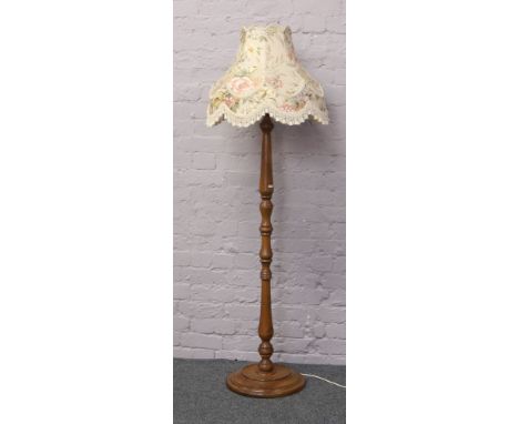 A carved and turned oak standard lamp with floral shade.