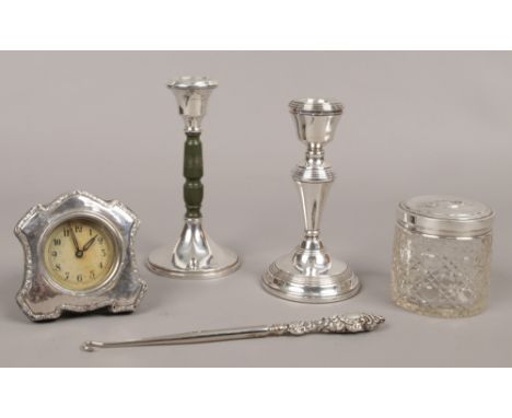 A collection of silver items to include a cut glass jar with silver lid, assayed Birmingham 1945, two silver candlesticks, si