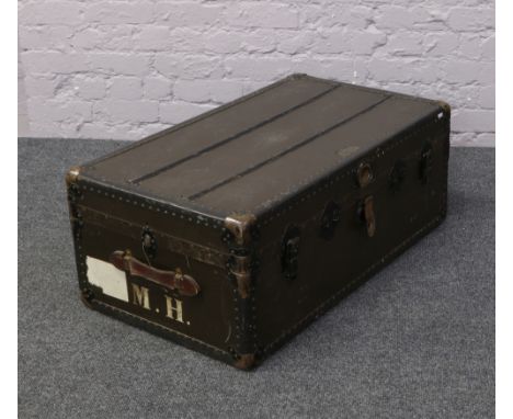 A vintage metal bound travel trunk with painted initials M.H