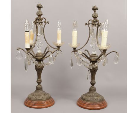 A pair of early - mid 20th century continental bronze three branch table lamps, adorned with cut glass finials and droplets a