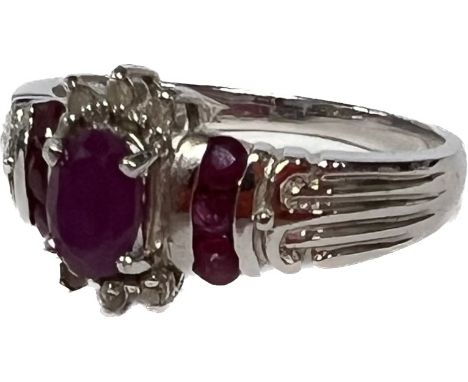 A 10ct white gold set with a central oval ruby flanked six round diamond chips, the two shoulders channel set with ssix round