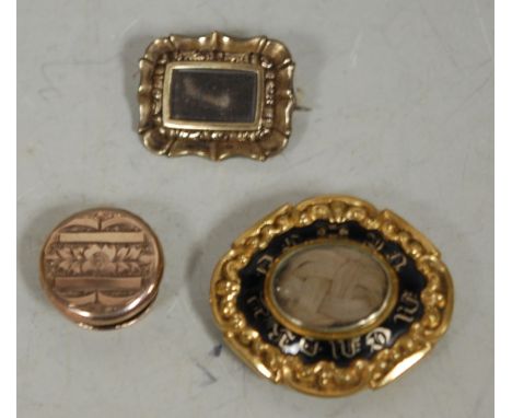 A Victorian pinchbeck and black enamel mourning brooch, set with a plait of hair under crystal, 3.5cm; one other smaller pinc