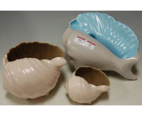 Two 1960s Poole Pottery two-tone conch shaped shell vases; together with another Poole Pottery shell vase (3) 