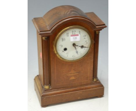 An Edwardian mahogany and satinwood inlaid mantel clock of architectural form, having an enamel dial with Arabic numerals and