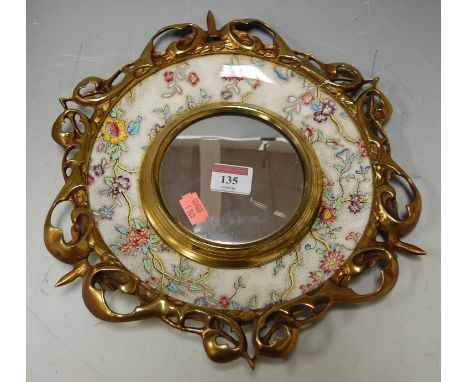 A circular convex wall mirror within a gilt and ceramic surround