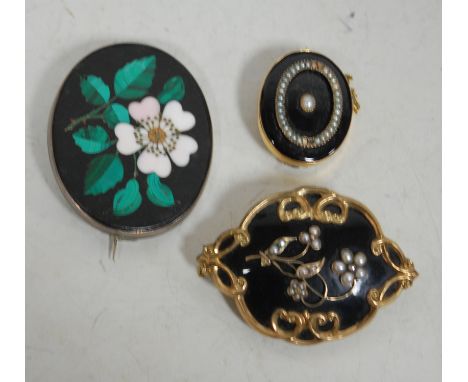 A Victorian pinchbeck black enamel and seed pearl set mourning brooch, inscribed verso, 6cm; one other smaller seed pearl set