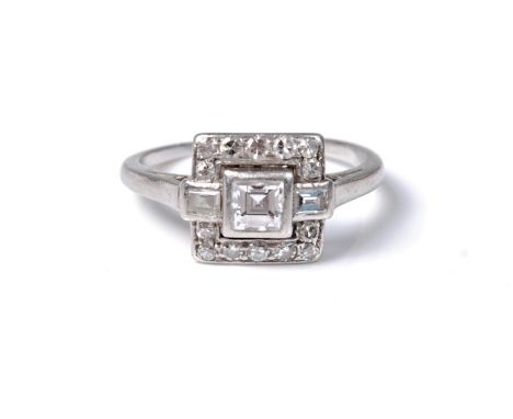 An Art Deco diamond ring, the central princess cut diamond set to either side with a single bagette cut diamond, surrounded a