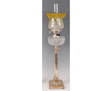 A late Victorian silver plated Corinthian column pedestal oil lamp, having a yellow tinted acid etched handkerchief glass sha