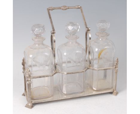 A Victorian silver plated three bottle decanter stand, having swing carry handles, the decanters with faceted stoppers, cante
