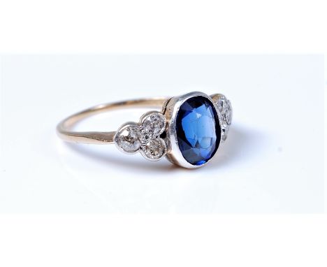 An 18ct synthetic sapphire and diamond ring, the oval sapphire, approx. 8.3 x 7mm, in a milligran mount, set to either side w