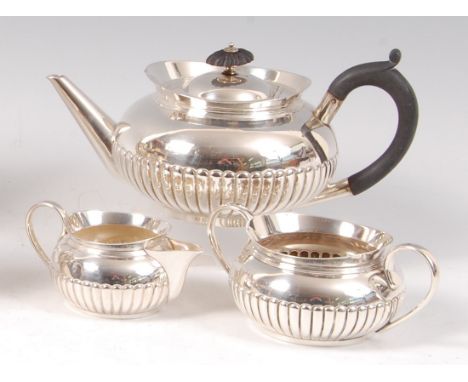 A late Victorian silver three-piece teaset, comprising teapot, twin handled sugar and cream, each of half-reeded squat circul